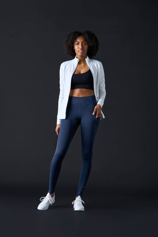Tall woman wearing leggings, sports bra, and athletic zip jacket