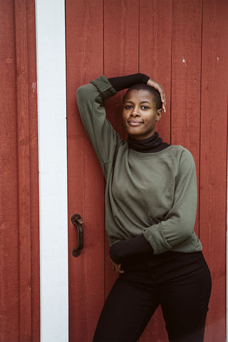 green crewneck sweater in front of a barn