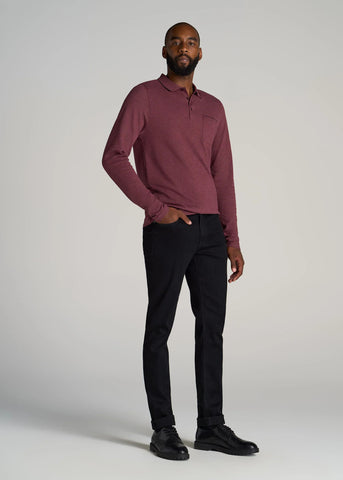 Tall man standing wearing black pants and maroon colored long sleeve polo