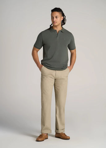 Man standing wearing khaki pants and olive colored polo shirt