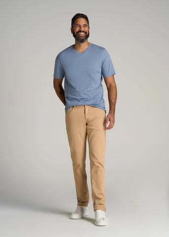 Tall man wearing sand colored pants and chambray blue v-neck t-shirt