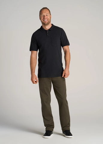 Tall man wearing black polo shirt with olive green straight leg jeans